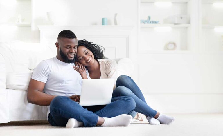 A couple and a real estate agent review documents at a kitchen table on closing day.